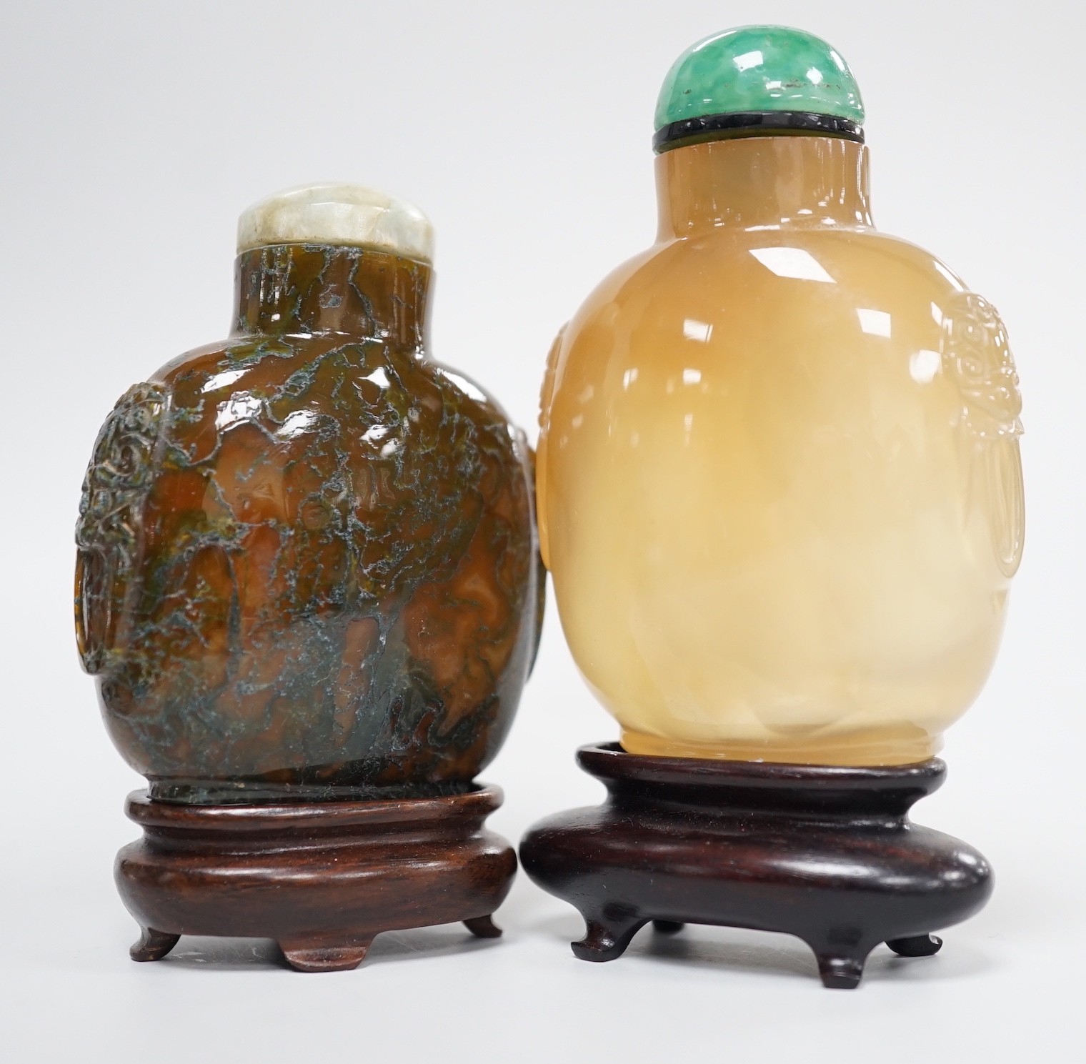 A Chinese honey coloured agate mask and ring handled snuff bottle and a dendritic chalcedony (moss agate) mask and ring handled snuff bottle, 5.7cm, both 1780-1880
